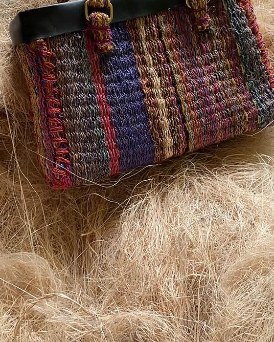 A dyed and woven plantain fibre handbag with a leather handle